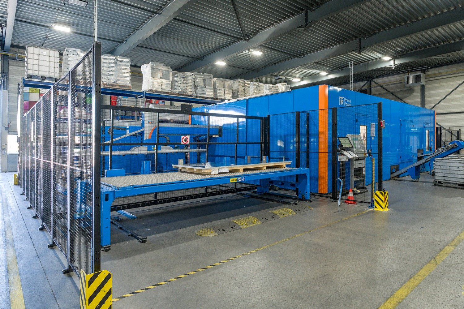Productiehal van VPT Versteeg met een moderne Prima Power-machine voor het snijden en bewerken van metaalplaten, omgeven door een veiligheidshek en industriële werkruimte.